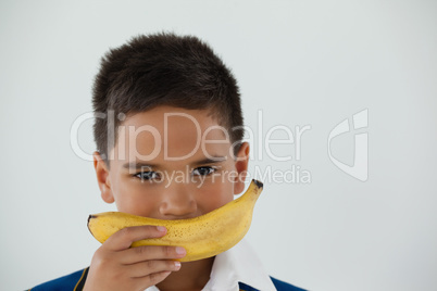 Schoolboy holding banana against white background