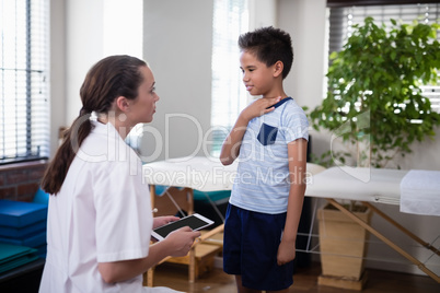 Female therapist looking at boy touching neck