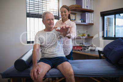 Smiling senior male patient and female doctor looking at hand