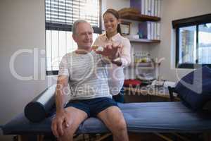 Smiling senior male patient and female doctor looking at hand