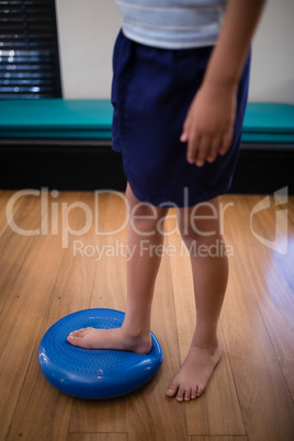 Low section of boy standing on large blue stress ball