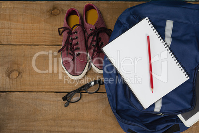 Shoes, spectacles, book, pencil, digital tablet and schoolbag on wooden table