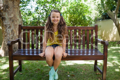 Portrait of smiling girl sitting on wooden bench