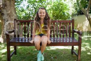 Portrait of smiling girl sitting on wooden bench