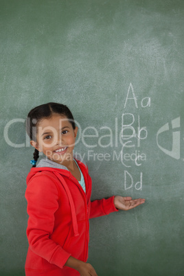 Young girl gesturing over chalk board