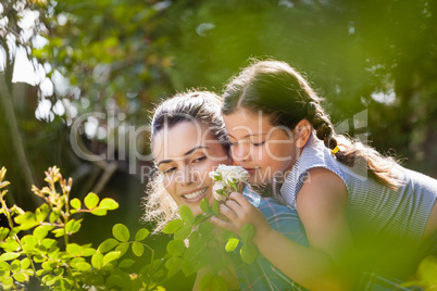 Girl smelling flowers while enjoying piggyback ride on mother