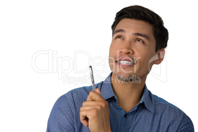 Businessman holding pen while looking away