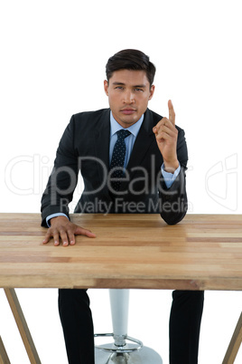 Portrait of businessman pointing upwards while sitting at table