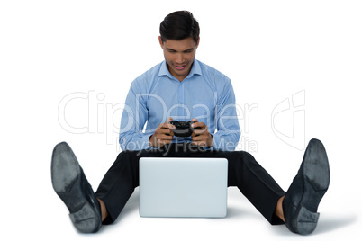 Full length of young businessman playing video game on laptop
