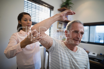 Female doctor examining elbow of male patient