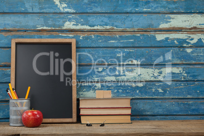 Stack of books, slate, apple and pen holder