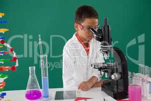 Smiling schoolboy looking through microscope in laboratory