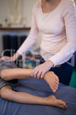 Female therapist examining leg of boy lying on bed