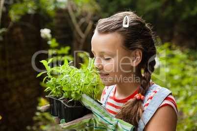 Girl with eyes closed smelling potted plants