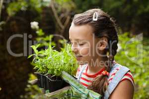 Girl with eyes closed smelling potted plants