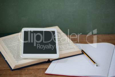 Digital tablet and books on table in classroom