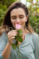 Beautiful woman with eyes closed smelling pink rose