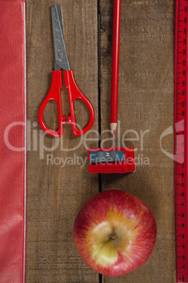 Apple and school supplies on wooden table