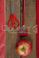 Apple and school supplies on wooden table