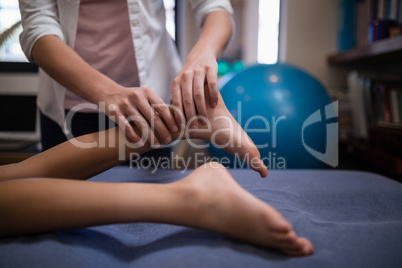 Midsection of female therapist massaging leg while boy lying on bed