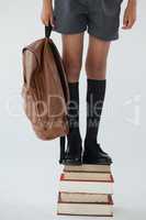 Schoolboy standing on stack of book against white background