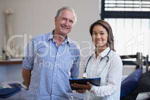 Portrait of smiling senior male patient and female therapist discussing file