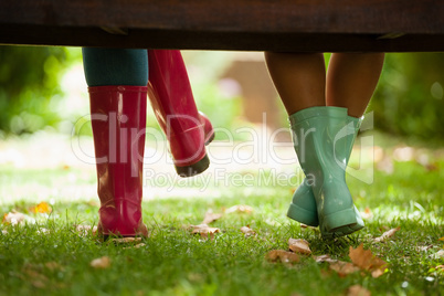 Low section of woman and daughter sitting on bench