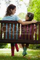 Rear view of smiling woman and girl sitting on bench