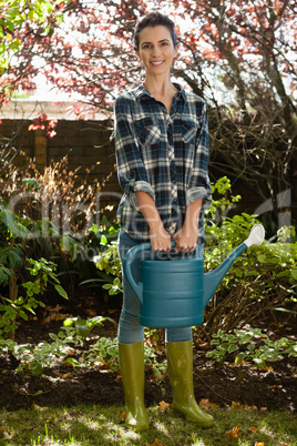 Portrait of smiling woman holding watering can