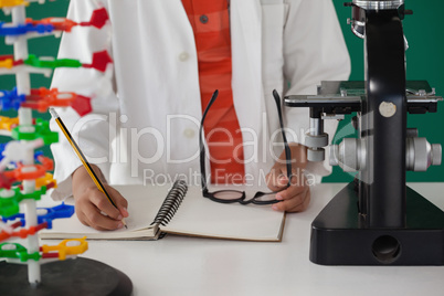 Schoolboy writing on book against green background