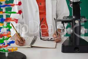 Schoolboy writing on book against green background