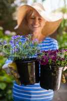 Smiling senior woman holding fresh flower pots