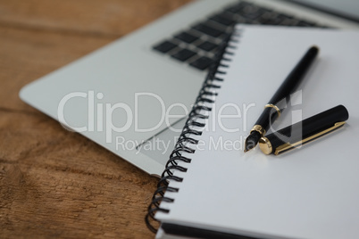 Laptop, pen, and diary on wooden background