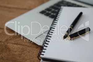 Laptop, pen, and diary on wooden background