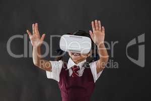 Schoolgirl using virtual reality headset against blackboard