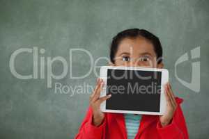 Young girl holding digital tablet against her face