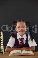 Schoolgirl reading a book against chalkboard