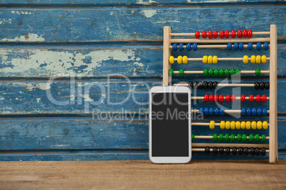 Abbacus game and smartphone against wooden background