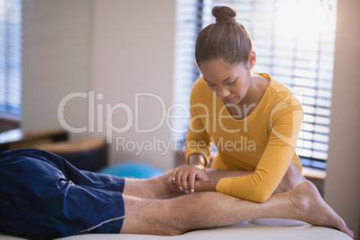 Young female therapist massaging calf of senior male patient