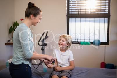 Smiling boy looking at female therapist scanning wrist