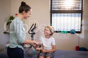 Smiling boy looking at female therapist scanning wrist