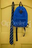 Schoolbag and tie hanging on door
