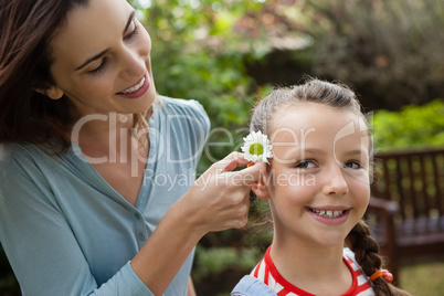 Smiling mother positioning white flower in hair of girl