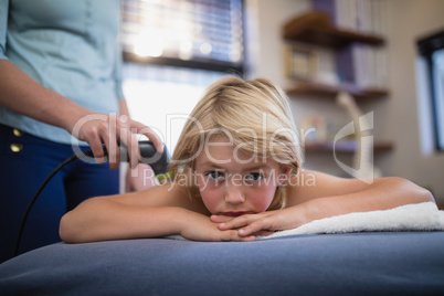 Portrait of boy lying on bed with female therapist using ultrasound scan