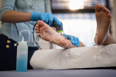 Low section of boy receiving ultrasound scan on feet from female physiotherapist