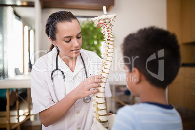 Young female therapist explaining boy with artificial spine