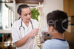 Young female therapist explaining boy with artificial spine