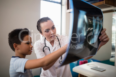 Female therapist and boy pointing at x-ray
