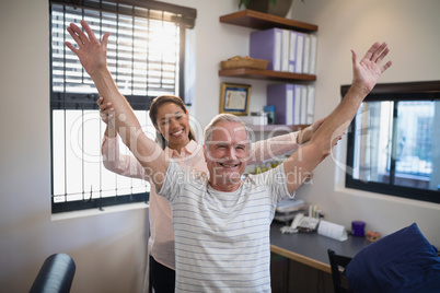 Smiling female doctor and male patient with arms raised