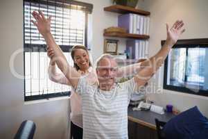 Smiling female doctor and male patient with arms raised